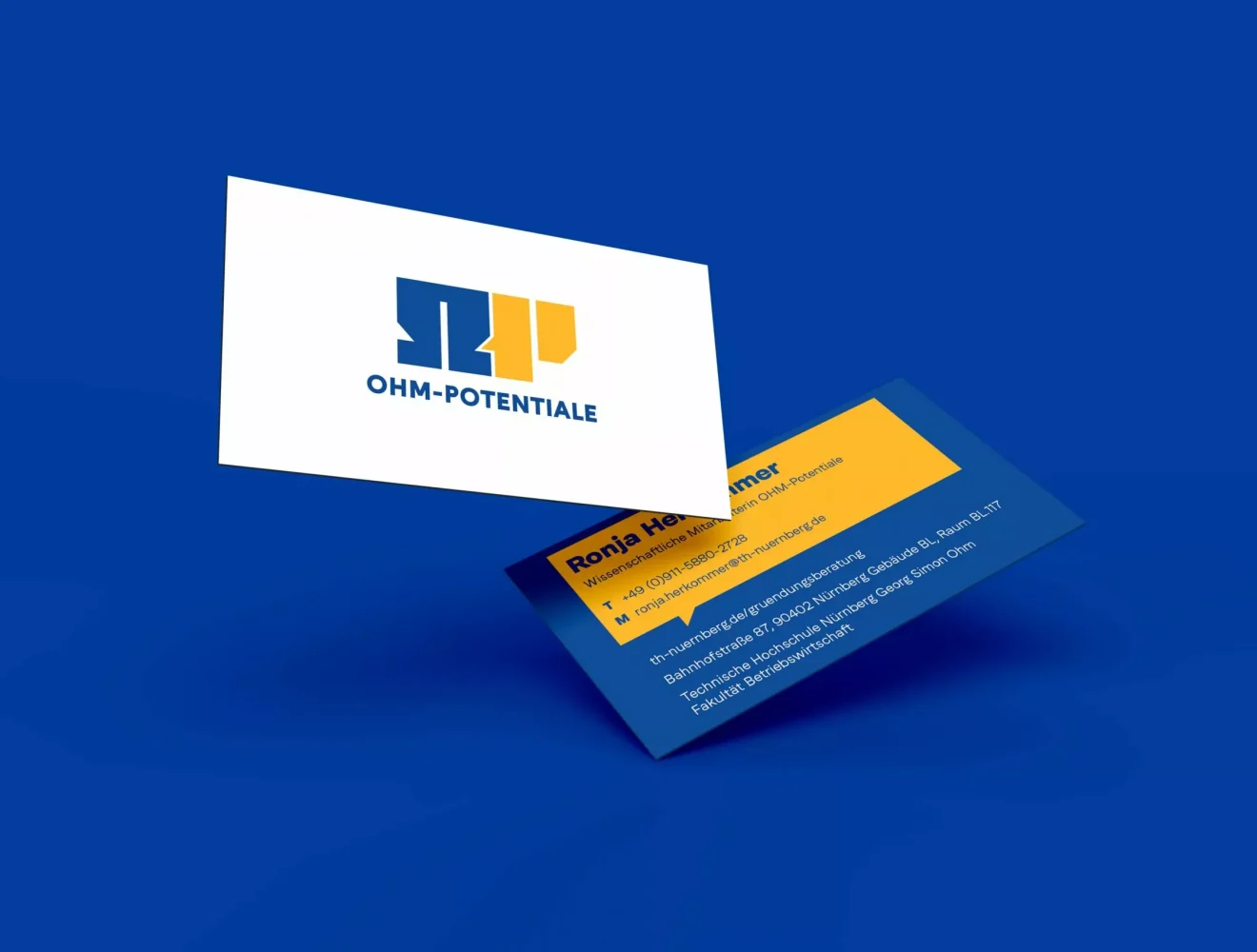 Zwei Visitenkarten schweben vor einem unifarbenen blauen Hintergrund. Auf der einen Karte ist das Logo der OHM-POTENTIALE zu sehen, auf der anderen die Kontaktdaten und ein gelber Bereich mit Text in Weiß und Gelb.
